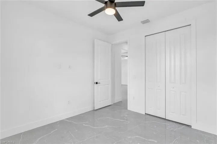 Unfurnished bedroom with ceiling fan and a closet