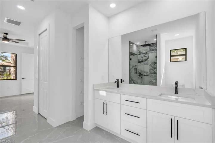 Bathroom with vanity, plenty of natural light, ceiling fan, and a shower with shower door