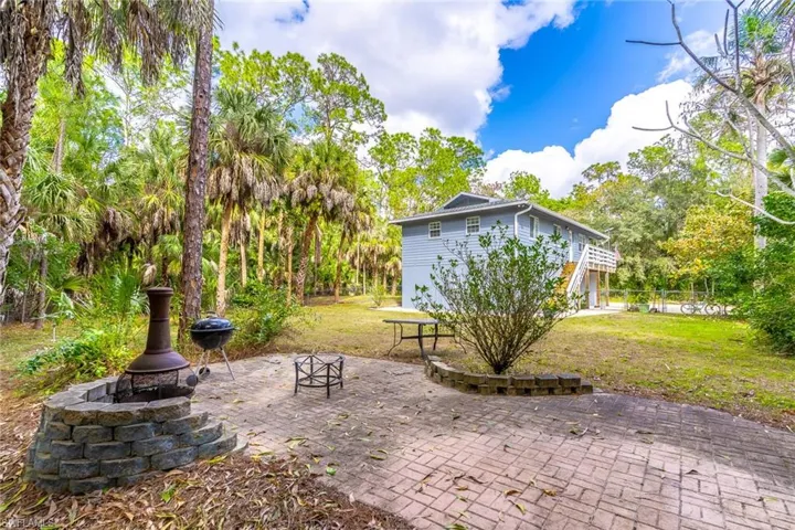 View of patio featuring an outdoor fire pit, view of scattered trees, and grilling area