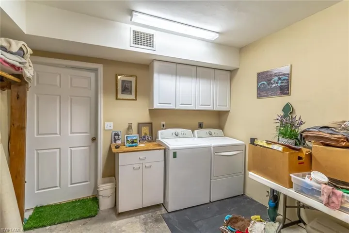 Downstairs Laundry room with cabinet space and washer and clothes dryer