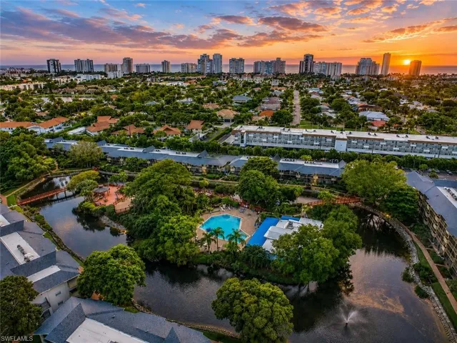 Community with multiple residential buildings, a central water feature, and extensive mature landscaping