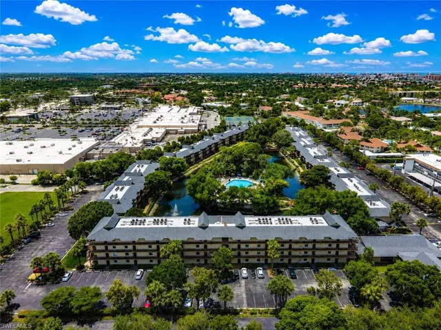 Aerial perspective showcasing a multi-story residential complex with a central pond and swimming pool