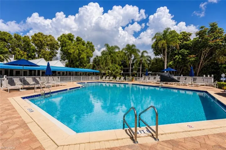 Community swimming pool featuring a brick paver deck and lounge seating
