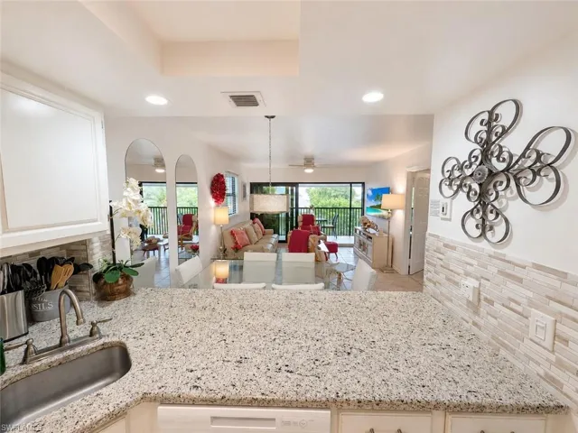 Kitchen featuring granite countertops, a stainless steel sink with a gooseneck faucet, white cabinetry, and a subway tile backsplash