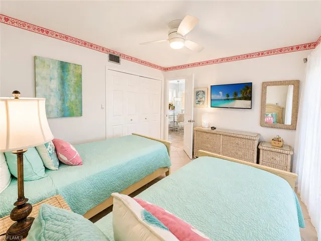 Bright bedroom featuring a ceiling fan, tiled flooring, and white bi-fold closet doors