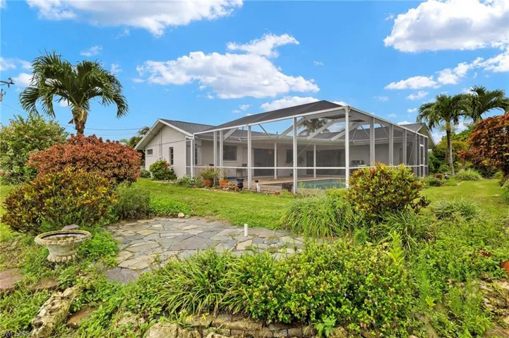 Rear view of property with a lawn and a lanai