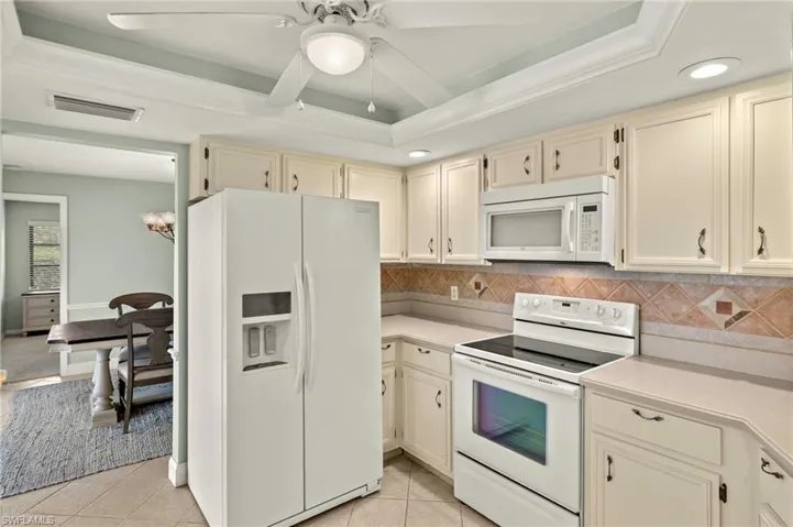Kitchen featuring white appliances, cream cabinets, light countertops, tasteful backsplash, and recessed lighting