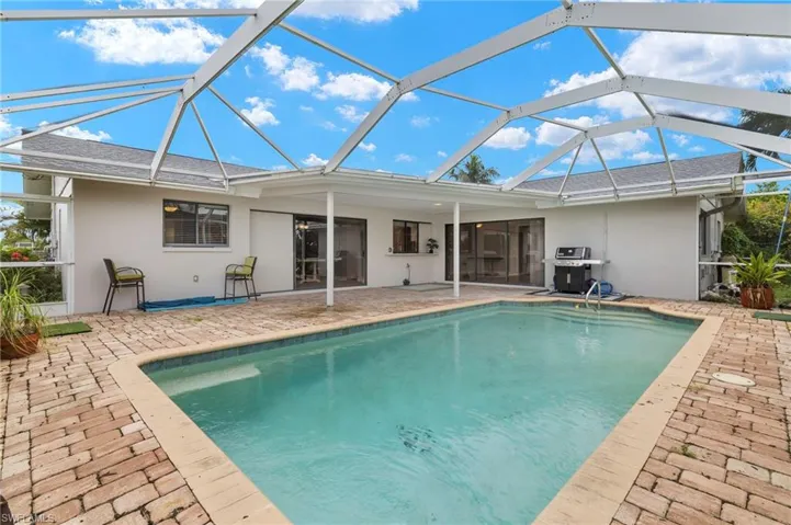 Swimming pool with a grill, a patio area, and glass enclosure