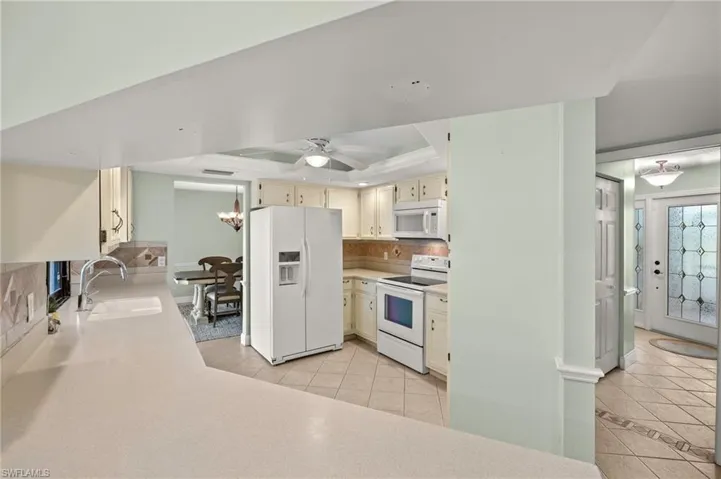 Kitchen with white appliances, a sink, a tray ceiling, and cream cabinets