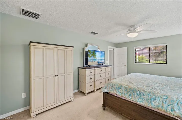 Bedroom with light carpet, a textured ceiling, baseboards, and ceiling fan