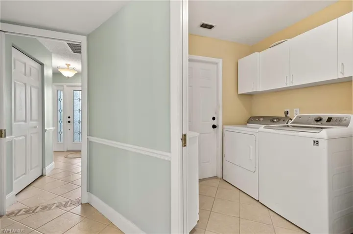 Washroom with light tile patterned floors, separate washer and dryer, cabinet space, and baseboards