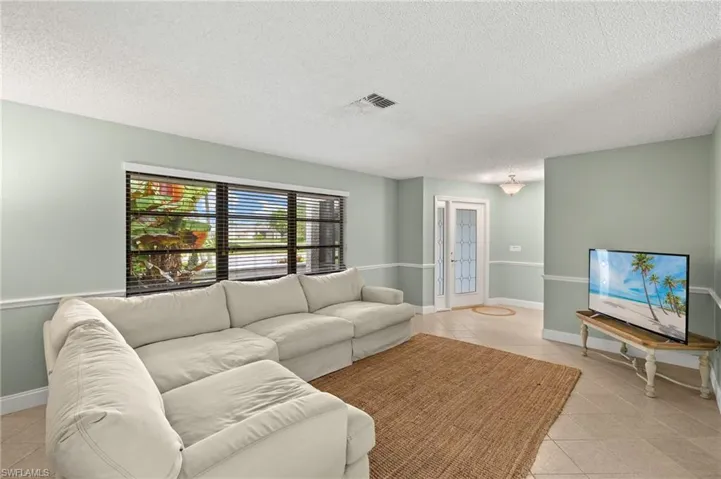 Living area featuring light tile patterned floors, a textured ceiling, french doors, and baseboards
