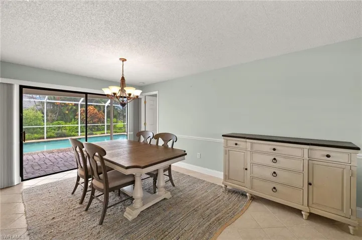 Dining space with a chandelier, light tile patterned floors, and a textured ceiling