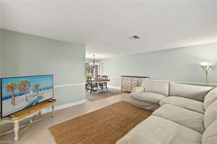 Living area featuring a chandelier, light tile patterned floors, a textured ceiling, and baseboards