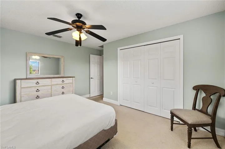 Bedroom with a closet, baseboards, light carpet, ceiling fan, and a textured ceiling