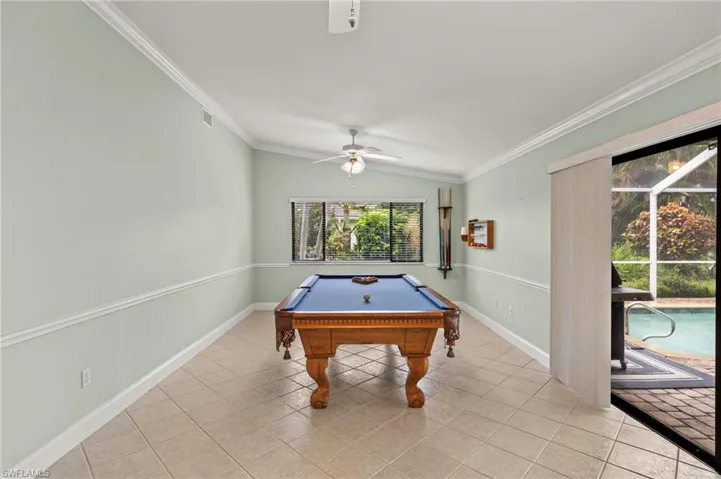 Playroom featuring ceiling fan, light tile patterned floors, crown molding, lofted ceiling, and baseboards