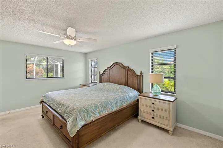 Bedroom with light colored carpet, baseboards, ceiling fan, and a textured ceiling
