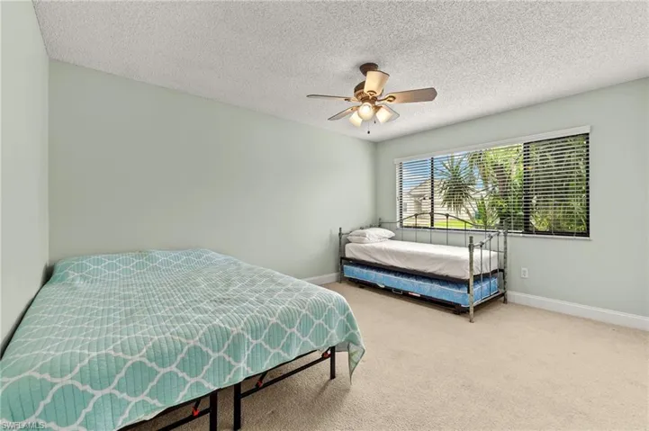 Carpeted bedroom featuring baseboards, a ceiling fan, and a textured ceiling