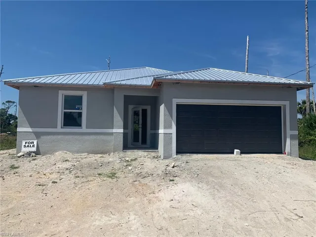 Single story home with a garage, stucco siding, and metal roof