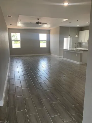 Unfurnished living room featuring plenty of natural light, a tray ceiling, and wood finish floors