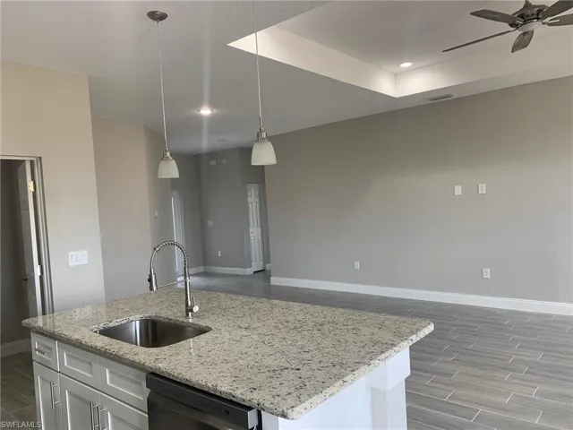 Kitchen featuring a ceiling fan, pendant lighting, baseboards, dishwashing machine, and a sink