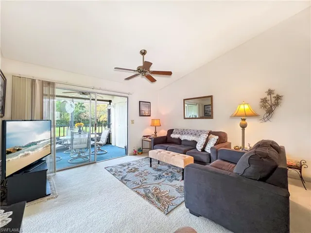 Carpeted living room featuring vaulted ceiling and ceiling fan