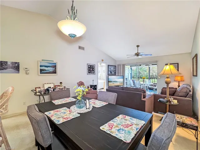 Dining space featuring high vaulted ceiling, light colored carpet, and ceiling fan