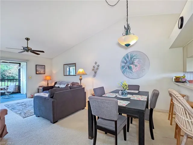 Dining space with light carpet, lofted ceiling, and ceiling fan