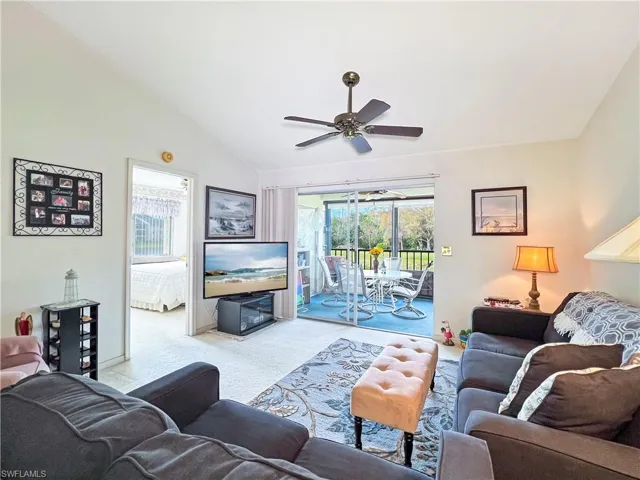 Living room featuring lofted ceiling, ceiling fan, light colored carpet, and a healthy amount of sunlight