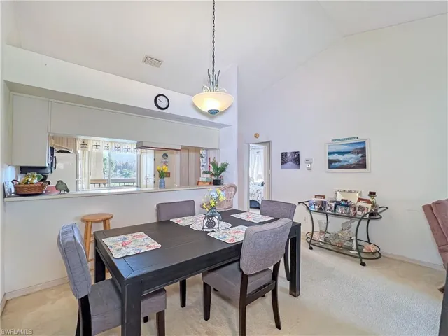 Dining area featuring high vaulted ceiling and light colored carpet