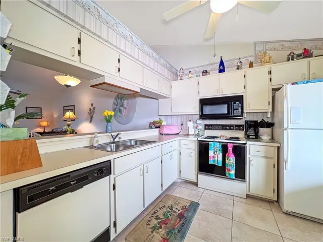 Kitchen featuring white cabinetry, sink, white appliances, ceiling fan, and light tile patterned floors