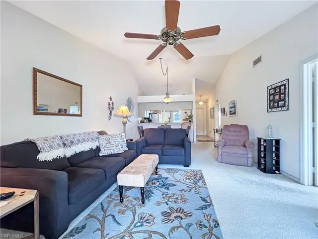 Carpeted living room with lofted ceiling and ceiling fan