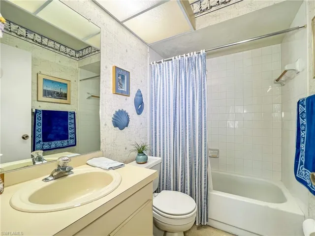 Full bathroom with shower / tub combo with curtain, toilet, and vanity