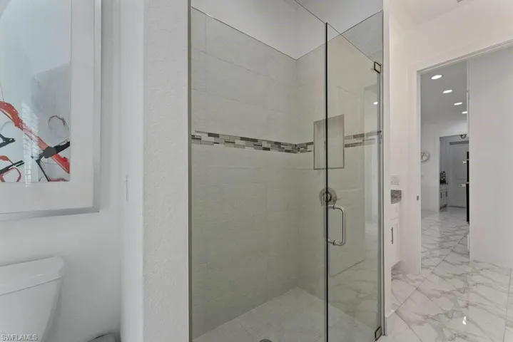 Glass-enclosed shower with subway tile surround, accent mosaic band, and built-in niche