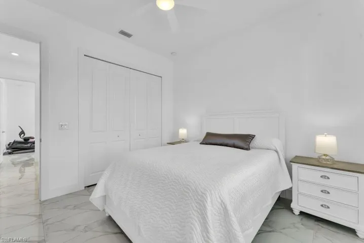 Bedroom featuring white walls, large bi-fold closet doors, and white marble-look flooring