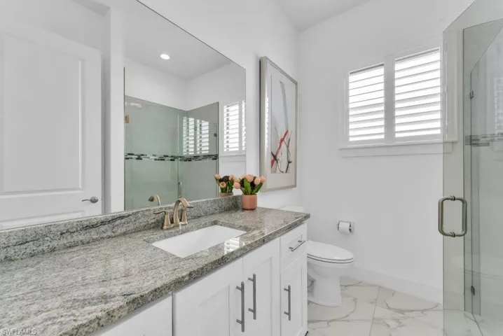 Bathroom featuring a vanity with a stone countertop, an undermount sink, and brushed nickel fixtures