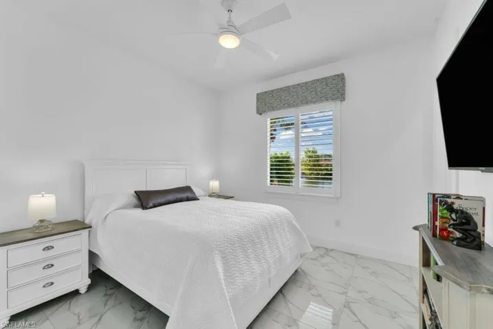 Bedroom featuring white walls and a white ceiling fan with integrated lighting
