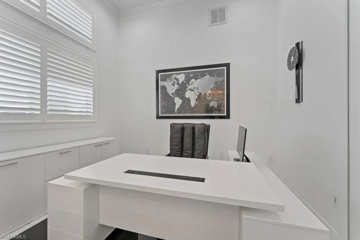Dedicated workspace featuring high ceilings, white walls, and built-in white cabinetry with chrome hardware