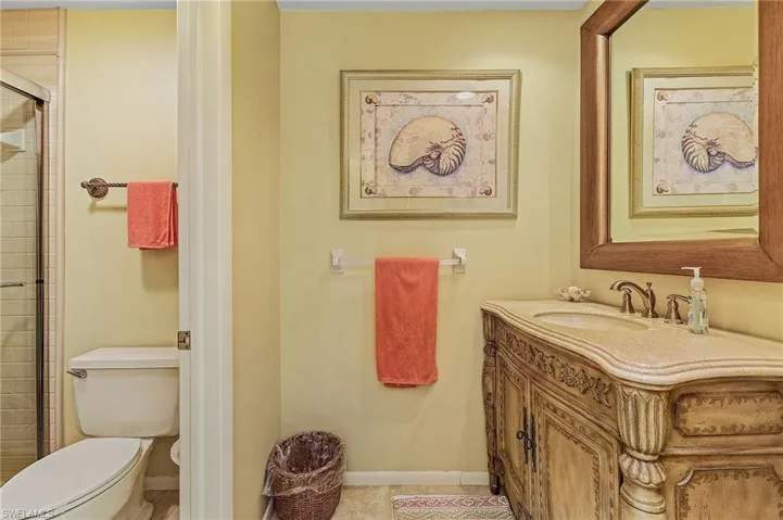 Bathroom with a tile shower, toilet, baseboards, tile patterned flooring, and vanity