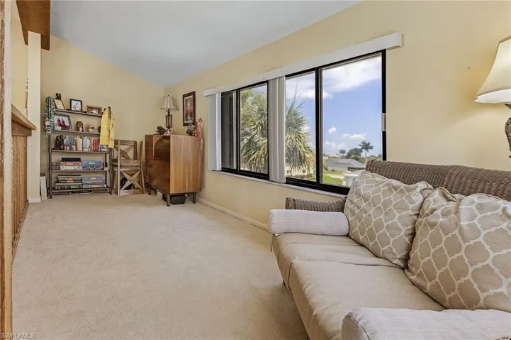 Carpeted living area with baseboards and lofted ceiling