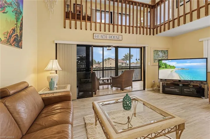 Living room featuring baseboards, wood finished floors, and a towering ceiling