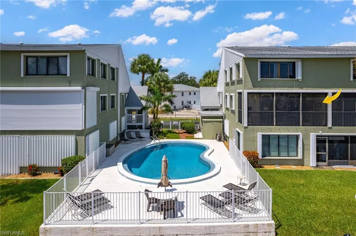 Community pool with a fenced backyard, a patio, and a lawn