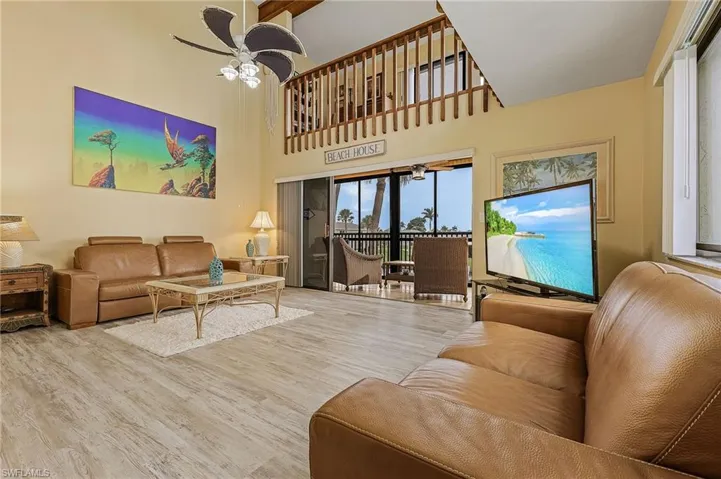 Living room featuring ceiling fan, a towering ceiling, and wood finished floors
