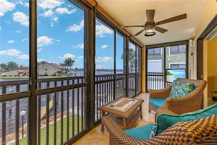 Sunroom featuring tile patterned flooring, a water view, and a ceiling fan