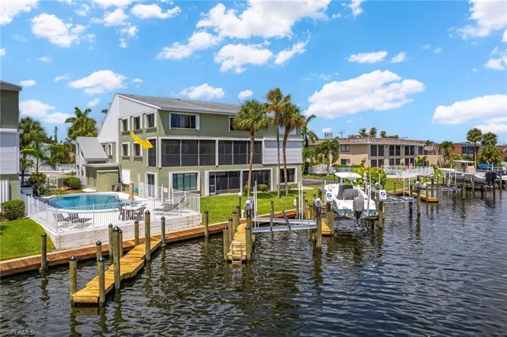 View of dock featuring a fenced in pool, a fenced backyard, a water view, a patio area, and boat lift