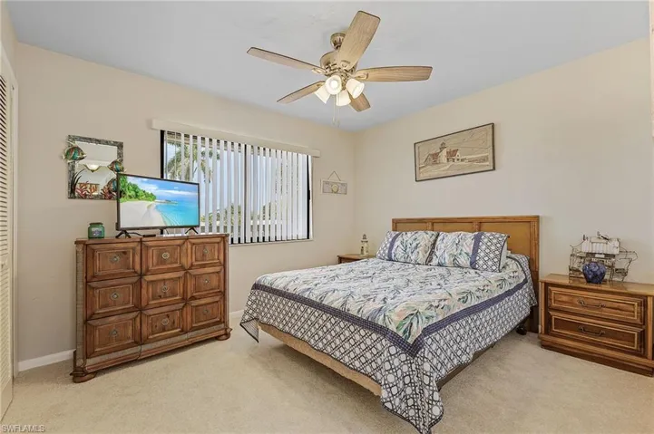 Bedroom featuring baseboards, a ceiling fan, and light colored carpet