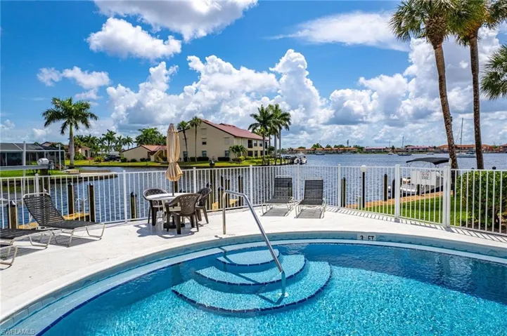 Community pool featuring fence, a water view, a patio area, and a residential view