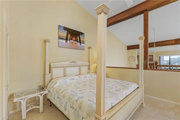 Tiled bedroom featuring baseboards, lofted ceiling, and ornate columns