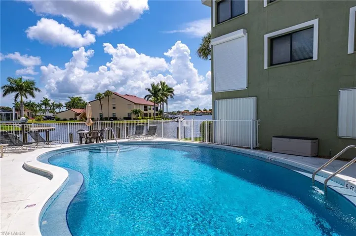 Community pool featuring a residential view, a patio, a water view, and fence