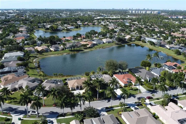Aerial view of property and surrounding area featuring nearby suburban area and a large body of water